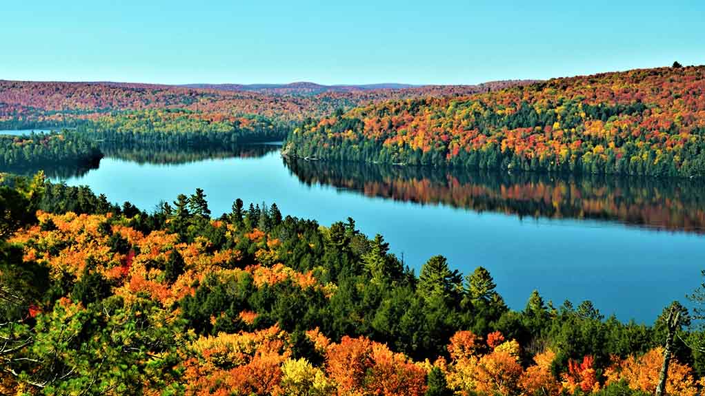 Colorful fall foliage surrounding a calm lake as seen from Booth’s Rock Trail in Algonquin Provincial Park, Ontario, Canada.